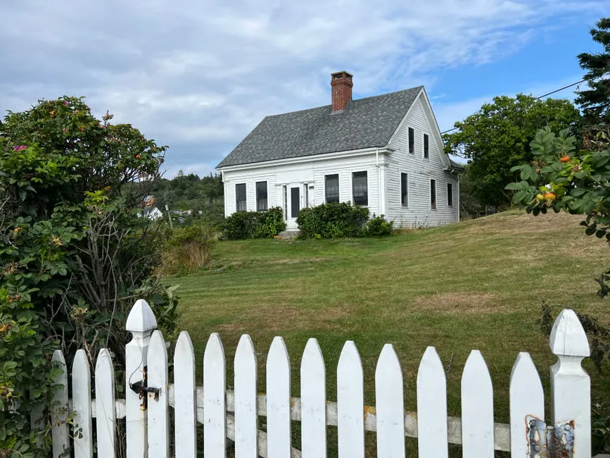 Weatherboard cottage with a picket fence on a hilly Hobart street in soft winter light